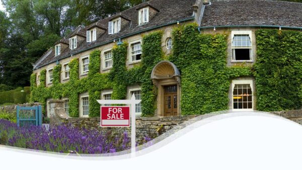 Image of a rustic inn with a "For Sale" sign in front.